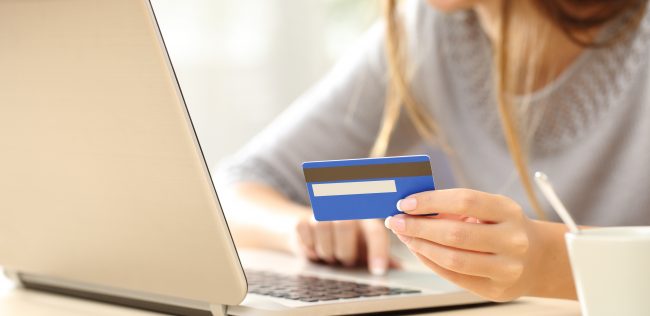 Close up of a happy woman hand buying online with a laptop and paying with a credit card
